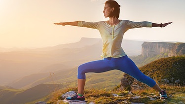 Eine junge Frau macht in den Bergen Yoga. | Bild: picture alliance / Zoonar | Ian Iankovskii
