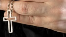 Hand hält Kreuzkette | Bild: picture alliance/imageBROKER